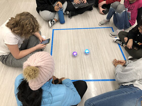 Kids sitting around sphero robots